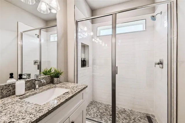 a bathroom with a granite countertop shower sink and mirror