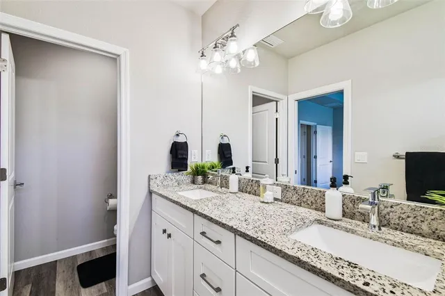 a bathroom with a granite countertop double vanity sink and a mirror