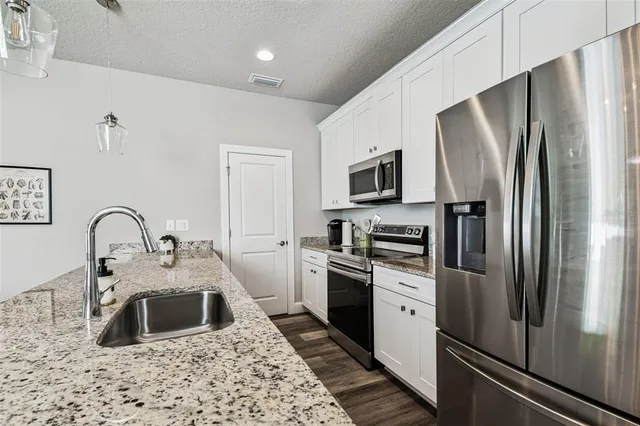 a kitchen with stainless steel appliances granite countertop a refrigerator a stove a sink and a microwave