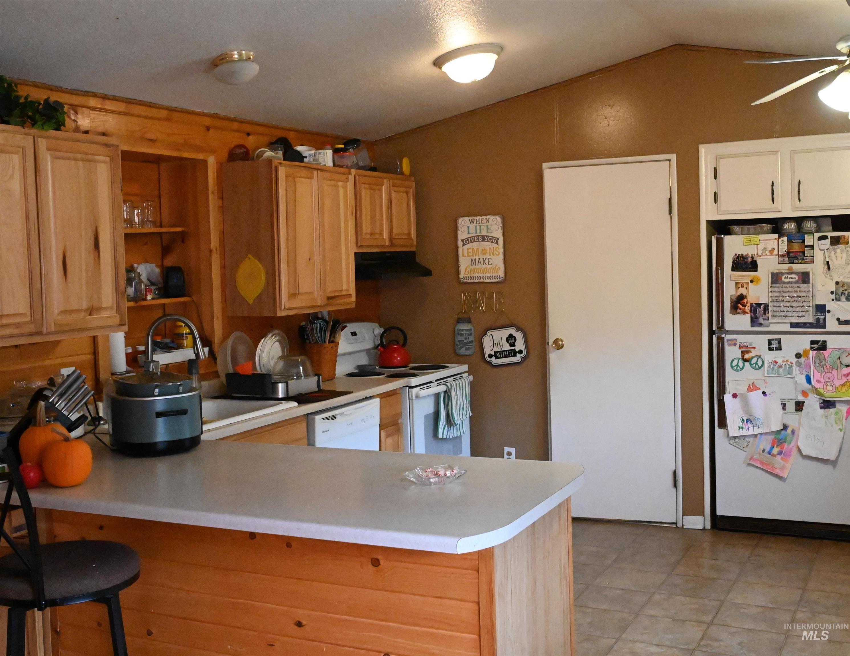 32288 Amos Bench Road Lenore, ID 83541 - Photo 12 of 24 Kitchen with white appliances, light countertops, a peninsula, lofted ceiling, and open shelves