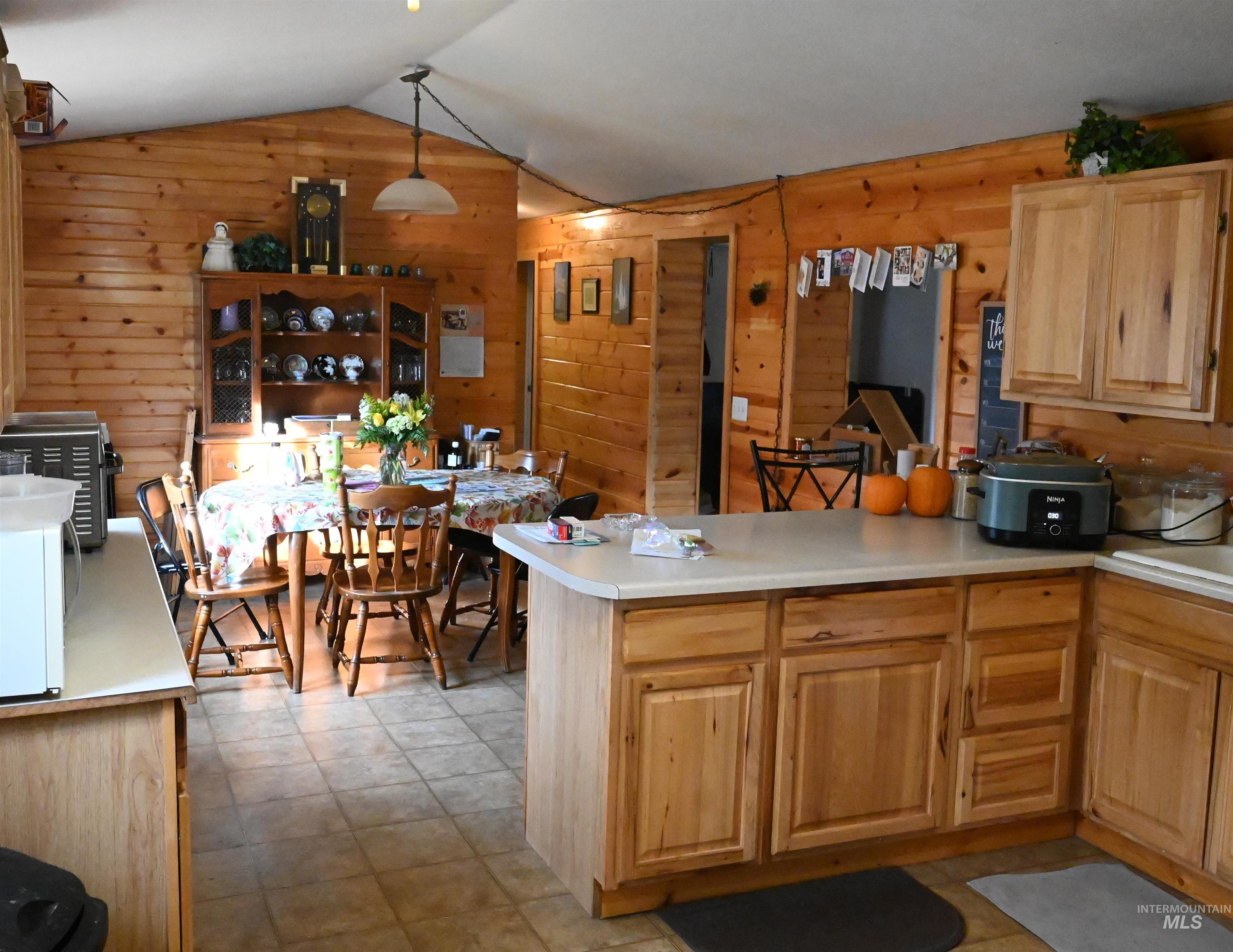 32288 Amos Bench Road Lenore, ID 83541 - Photo 9 of 24 Kitchen with light countertops, lofted ceiling, a peninsula, light brown cabinetry, and wooden walls