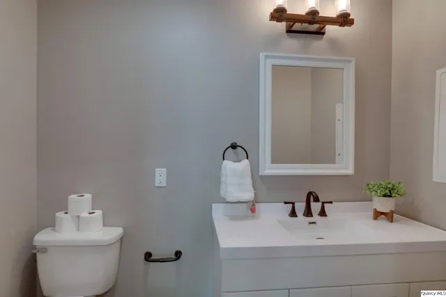 a bathroom with a granite countertop toilet sink and mirror