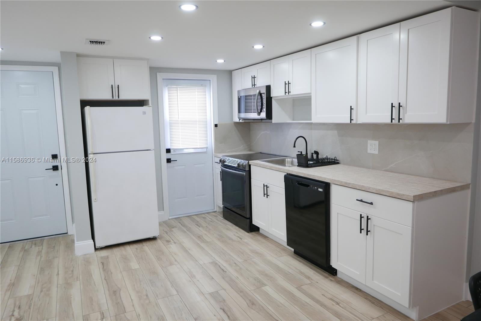 a kitchen with a sink a refrigerator a microwave and cabinets