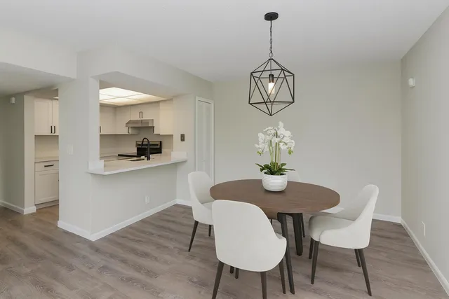 a dining room with wooden floor a chandelier a wooden table and chairs