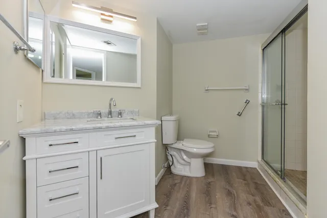 a bathroom with a granite countertop sink toilet a mirror and shower