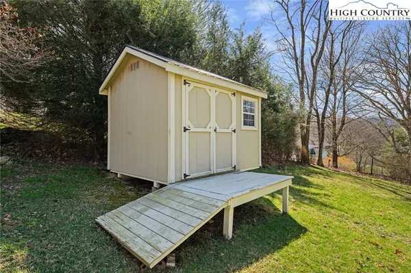 a view of an empty room with wooden floor and a ceiling fan