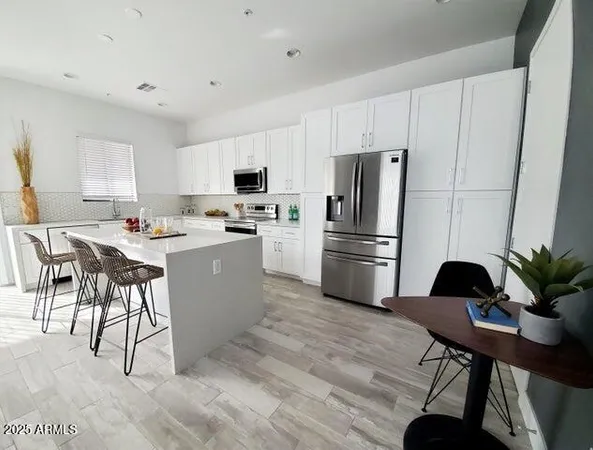 a kitchen with a refrigerator a stove a sink a dining table and chairs