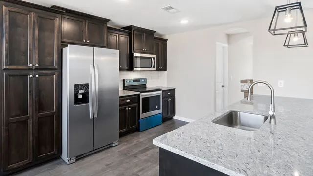 a kitchen with stainless steel appliances granite countertop a refrigerator a sink and a stove