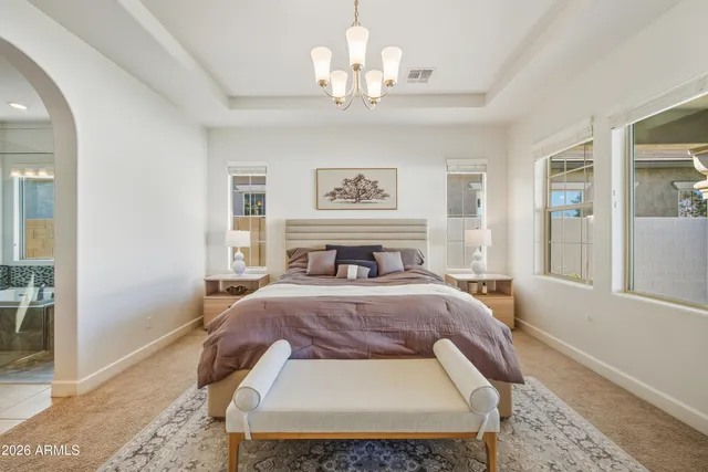 a bed sitting in a bedroom and chandelier