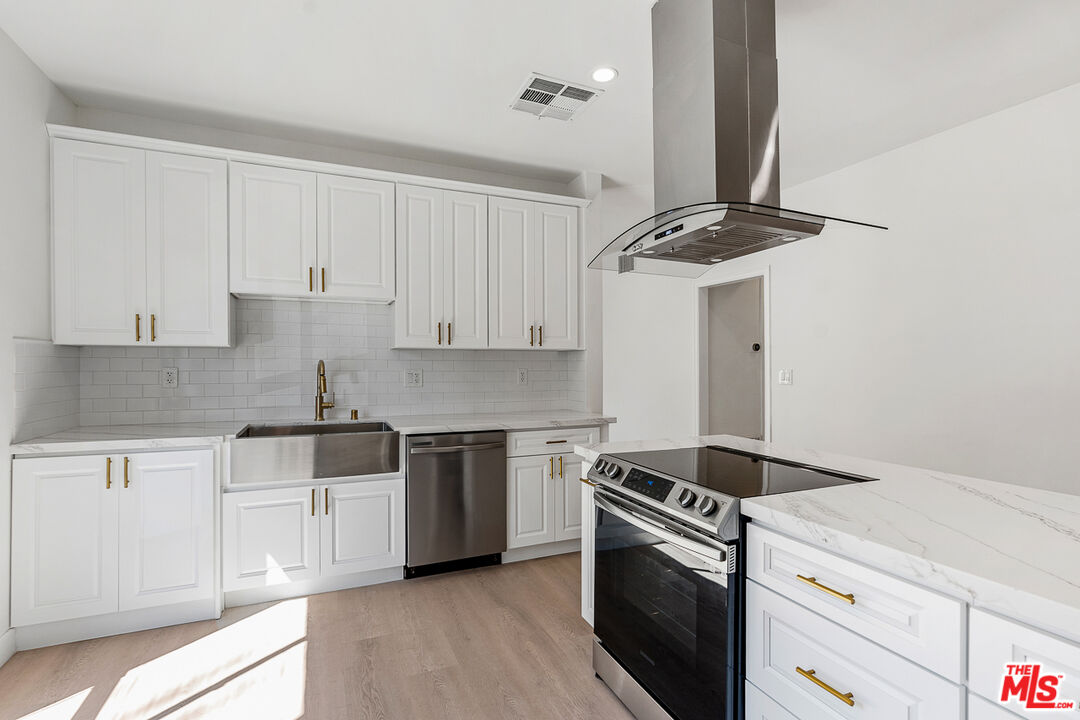 a kitchen with stainless steel appliances granite countertop white cabinets and a stove