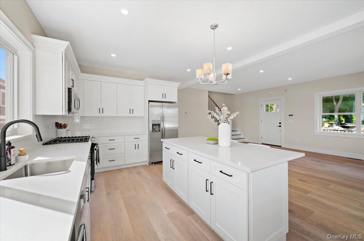 395 5th Avenue New Rochelle, NY 10801 - Photo 10 of 26 a kitchen with a sink dishwasher a stove a dining table and chairs with wooden floor
