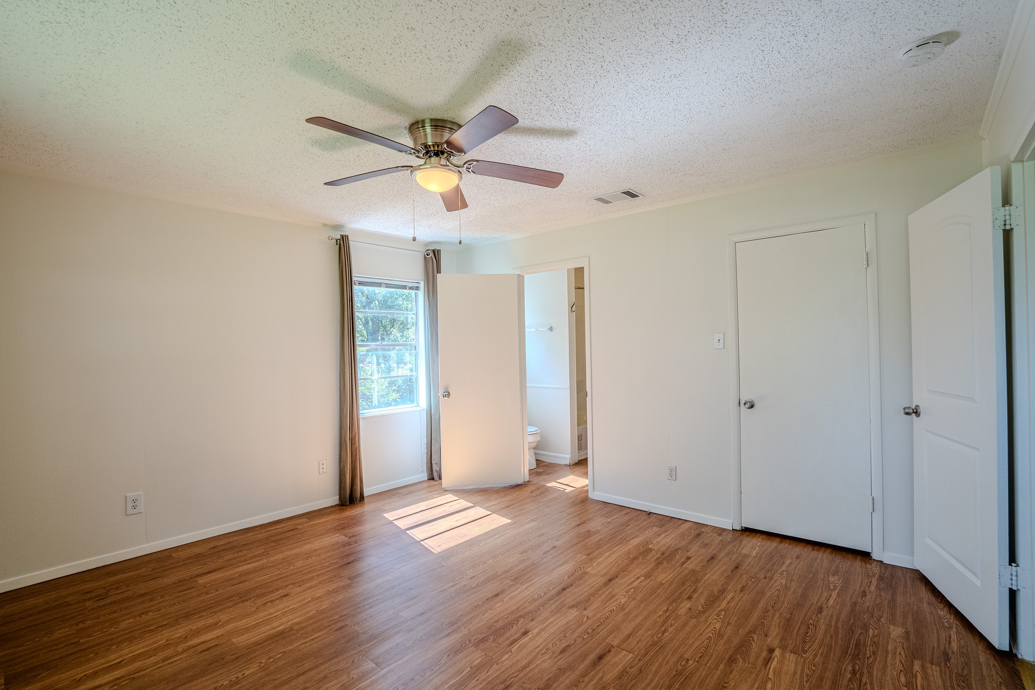 16013 Edwards Drive Austin, TX 78734 - Photo 13 of 18 Well-lit sleeping quarters with a ceiling fan, durable laminate flooring, and an adjoining bathroom.
