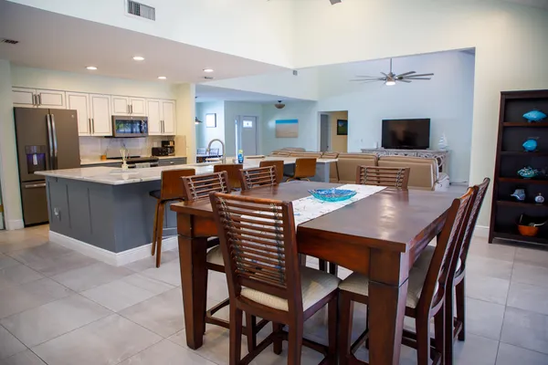 a view of a dining room and livingroom with furniture a flat screen tv and a refrigerator