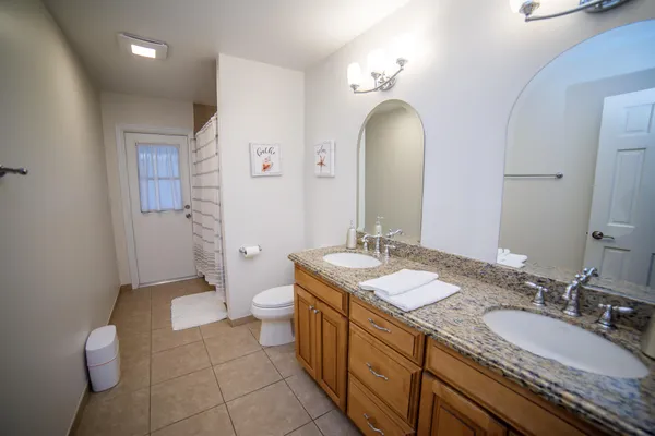 a spacious bathroom with a granite countertop sink a toilet and a mirror