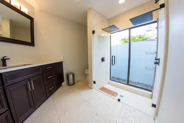 a spacious bathroom with a double vanity sink toilet mirror and shower