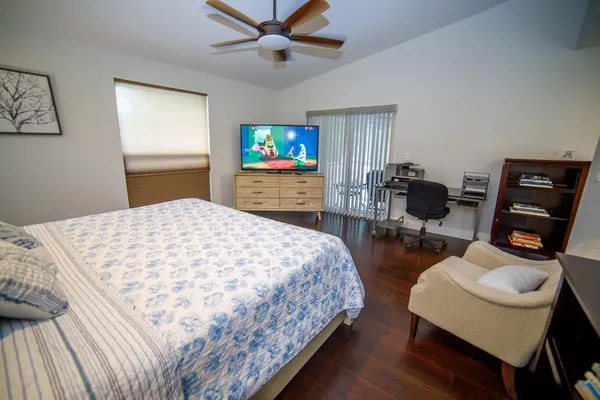 a bedroom with a bed a desk and chair with wooden floor