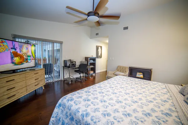a bedroom with a bed a dresser and wooden floor