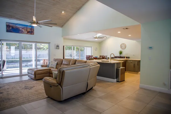a living room with couches and kitchen view with wooden floor