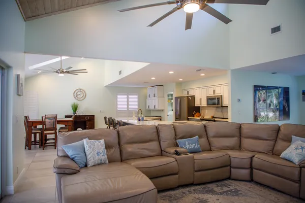 a living room with furniture kitchen view and a chandelier