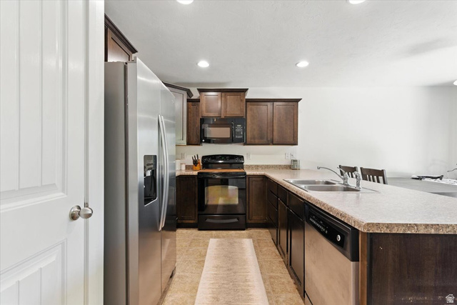 1187 Seraphim Court Layton, UT 84041 - Photo 6 of 18 Kitchen featuring black appliances, dark wood finish cabinets, a peninsula, light countertops, and recessed lighting
