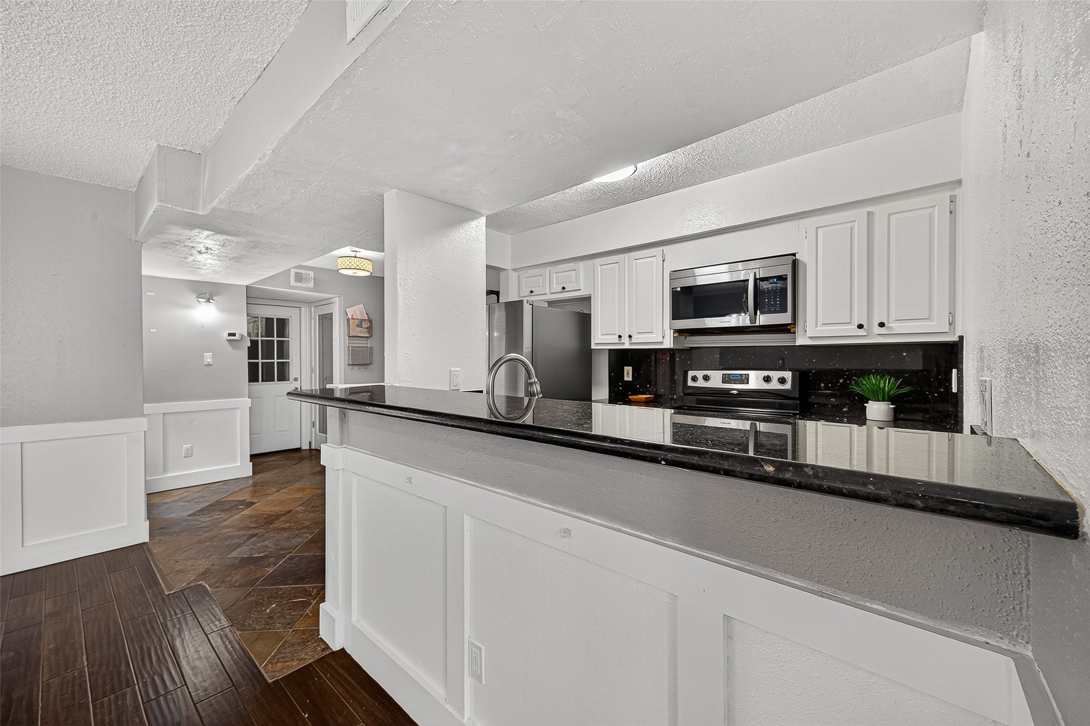 3200 South Gessner Road, Unit 224 Houston, TX 77063 - Photo 9 of 27 Kitchen features sleek black countertops, stainless steel appliances, and white cabinetry.