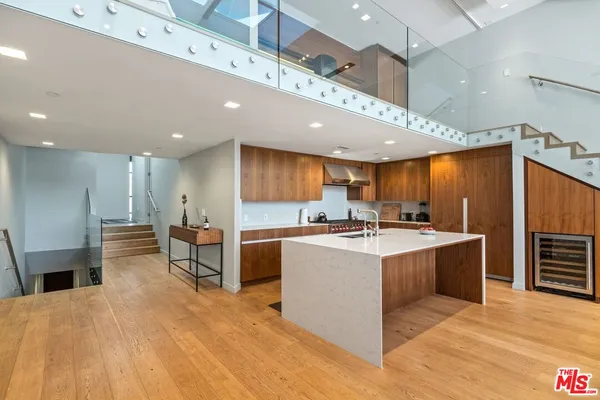 a large white kitchen with wooden floor and stainless steel appliances