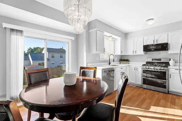 a kitchen with stainless steel appliances granite countertop a stove a refrigerator a dining table and chairs