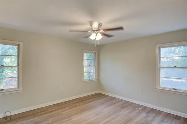 a view of an empty room with a window and wooden floor