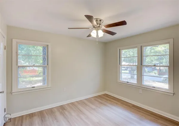 a view of an empty room with wooden floor and a window