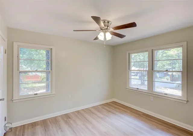 a view of an empty room with wooden floor and a window