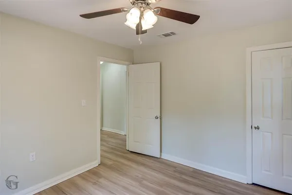 an empty room with wooden floor and a ceiling fan