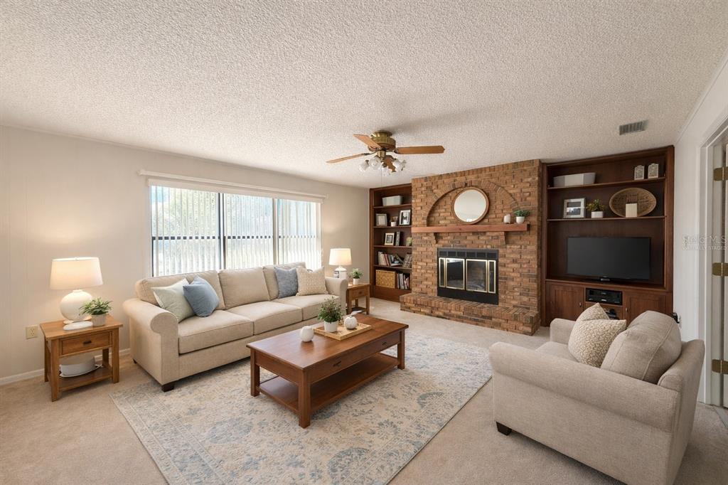 34847 Learn Road Leesburg, FL 34788 - Photo 8 of 25 a living room with furniture a fireplace and a flat screen tv