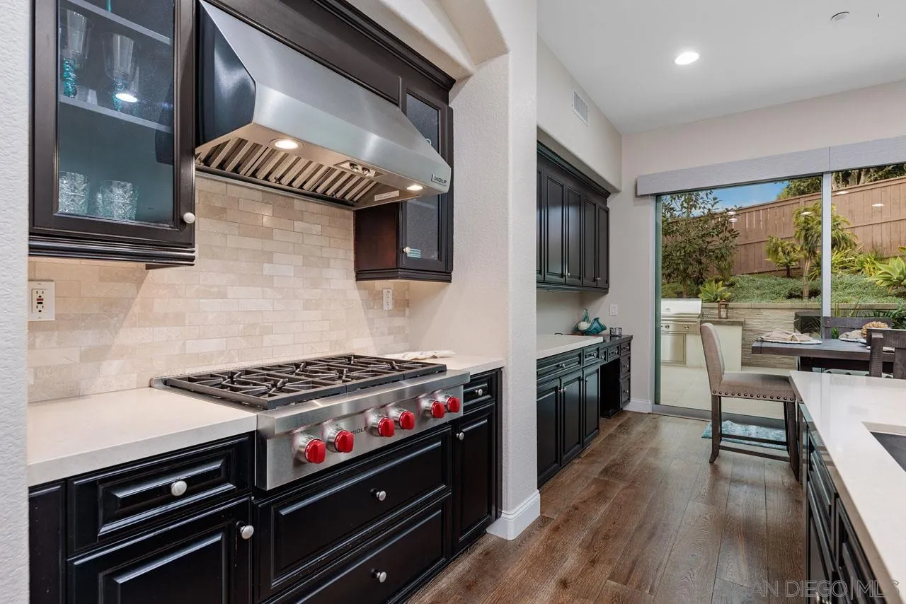 1460 Ravean Court Encinitas, CA 92024 - Photo 28 of 72 a kitchen with stainless steel appliances a stove a sink dishwasher a microwave oven and a dining table with wooden floor