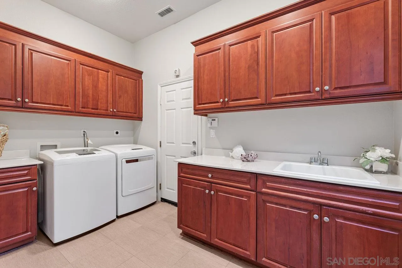 1460 Ravean Court Encinitas, CA 92024 - Photo 72 of 72 a utility room with granite countertop cabinets washer and dryer