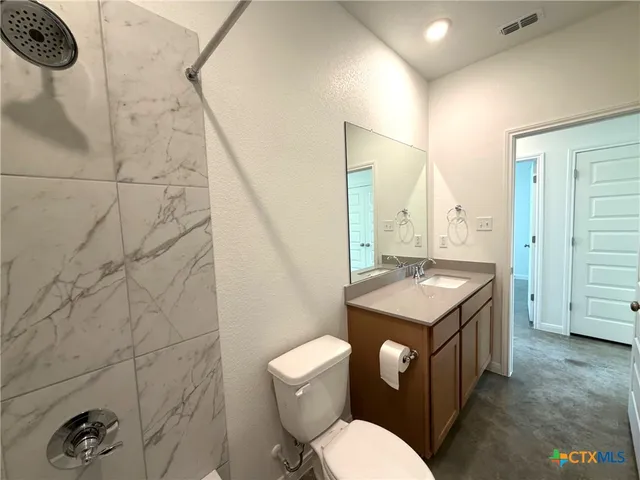 a bathroom with a granite countertop toilet sink and mirror