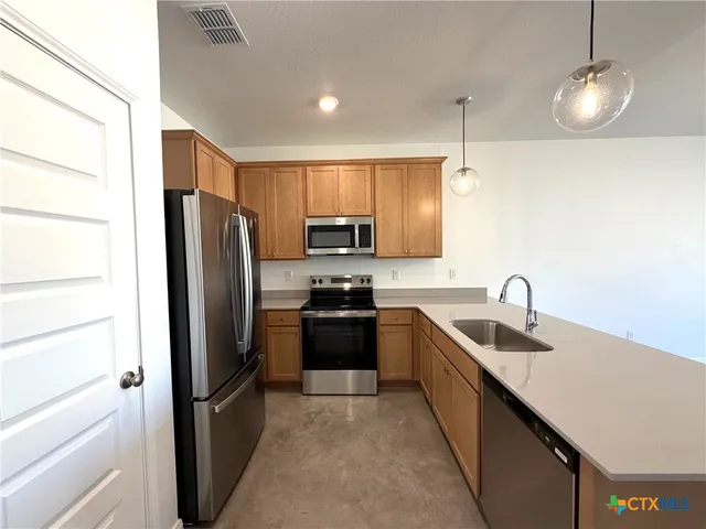 a kitchen with stainless steel appliances granite countertop a refrigerator a stove a sink and a microwave