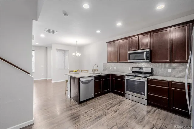 a kitchen with stainless steel appliances granite countertop wooden cabinets a stove a sink and dishwasher