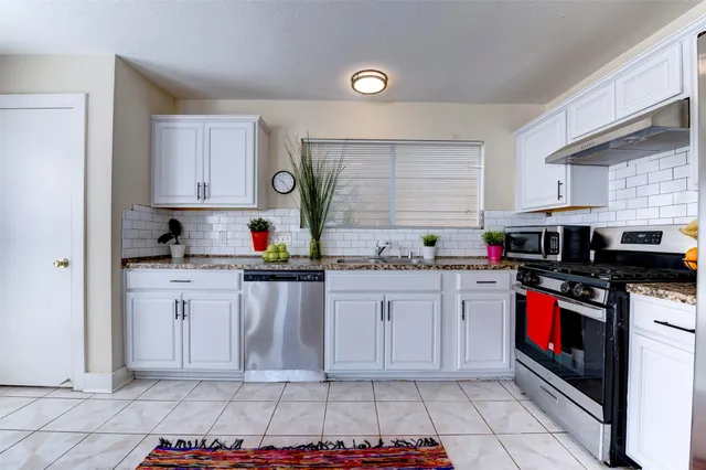 a kitchen with granite countertop a stove sink and cabinets