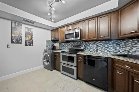 a kitchen with stainless steel appliances granite countertop a stove a sink and a microwave