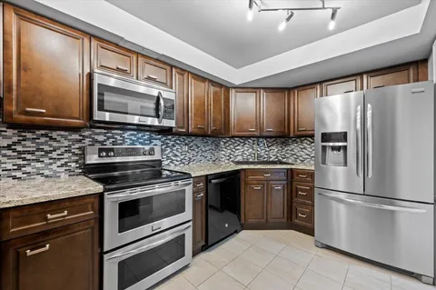 a kitchen with granite countertop wooden cabinets stainless steel appliances and a window