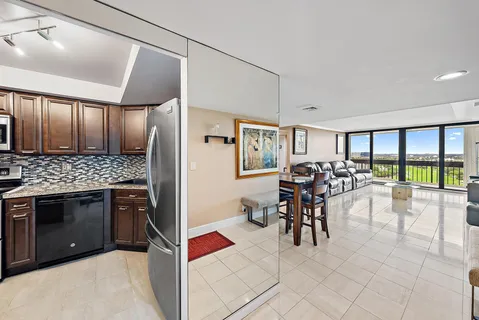 a kitchen with stainless steel appliances kitchen island granite countertop a table chairs in it and a window