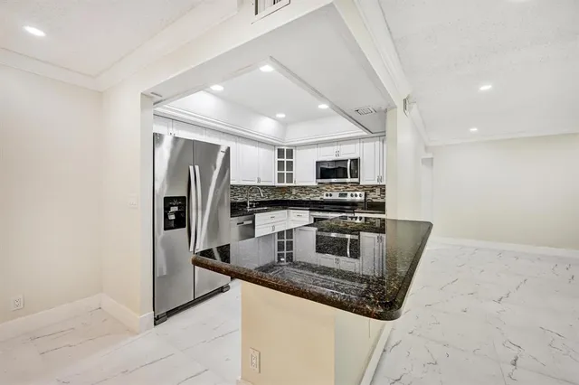 a kitchen with stainless steel appliances granite countertop a sink a stove a refrigerator a washer and dryer