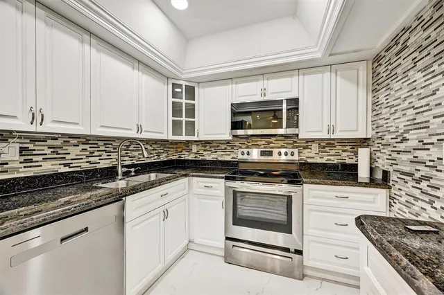 a kitchen with granite countertop a sink stove and microwave