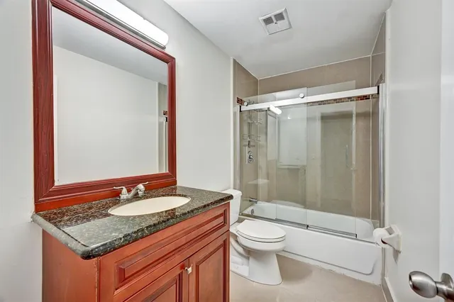 a bathroom with a granite countertop sink toilet and shower