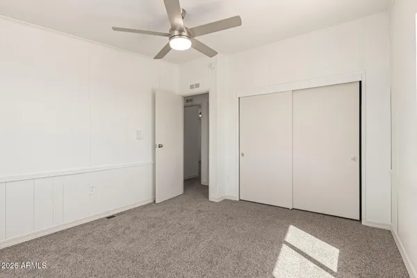 an empty room with closet and a chandelier fan