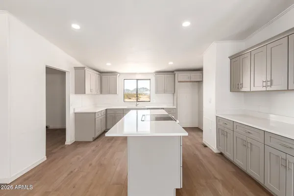 a large kitchen with stainless steel appliances kitchen island wooden floors and white walls