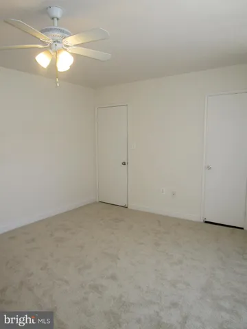 an empty room with a fan & a chandelier fan