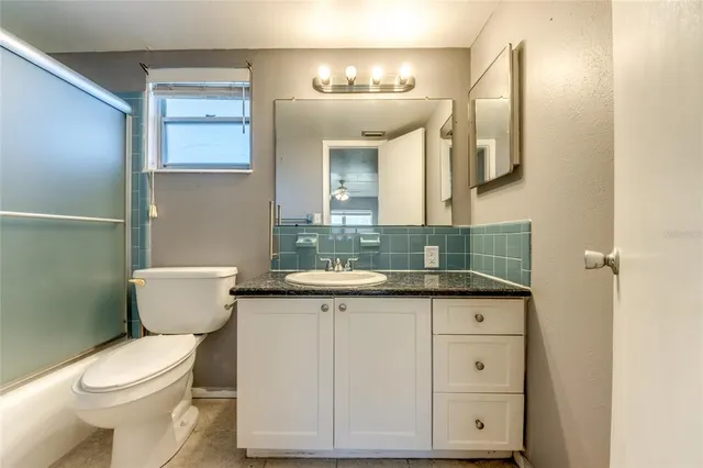 a bathroom with a granite countertop toilet sink and mirror