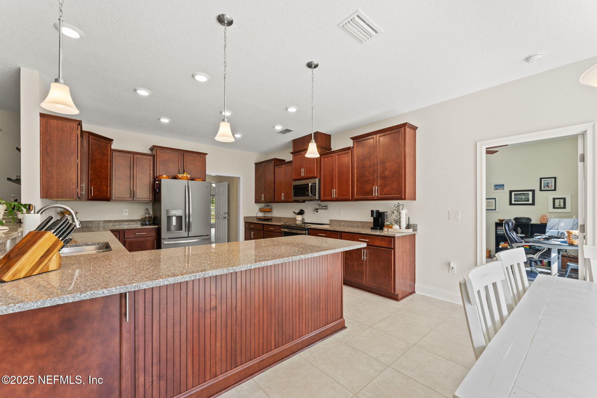 12869 Boney Road Jacksonville, FL 32226 - Photo 25 of 62 a kitchen with stainless steel appliances granite countertop a sink counter space chairs and wooden cabinets