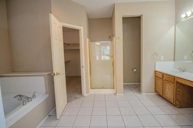 a spacious bathroom with a granite countertop sink a mirror and a bathtub